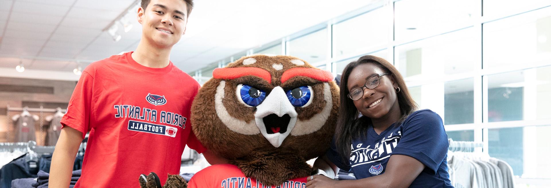 Two students next to FAU mascot Owlsley wearing FAU merchandise