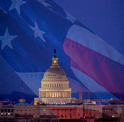blue background with american flag and the white house lit up at night